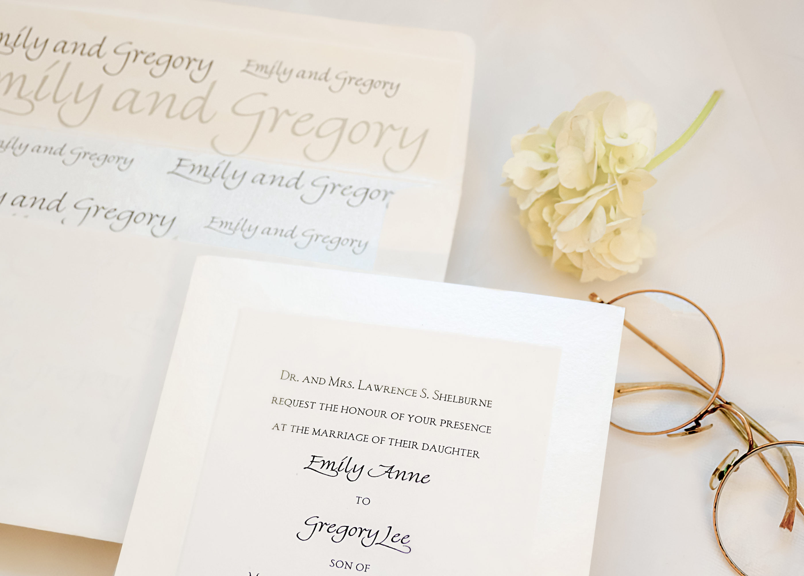 close photograph of cream colored invitation and envelope with bride and groom's names on inside of envelope