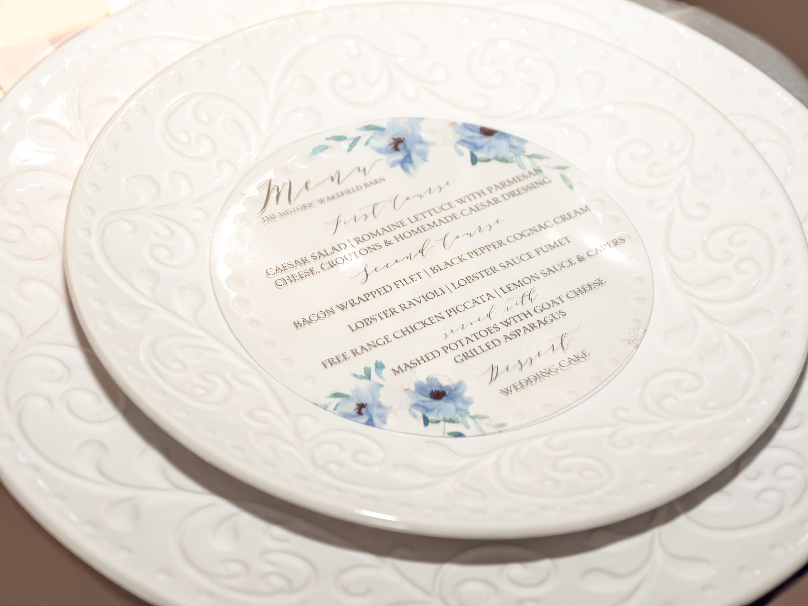 reception menu printed on clear acetate and cut into circle shape to lay inside of salad plate