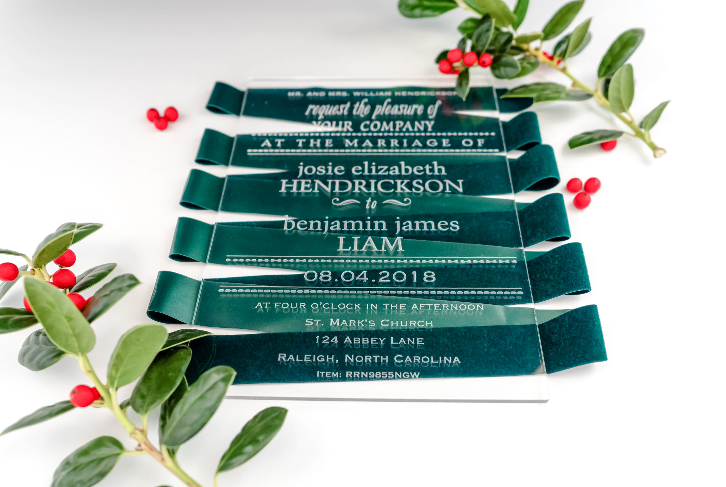 clear acetate wedding invitation laid on green velvet ribbon