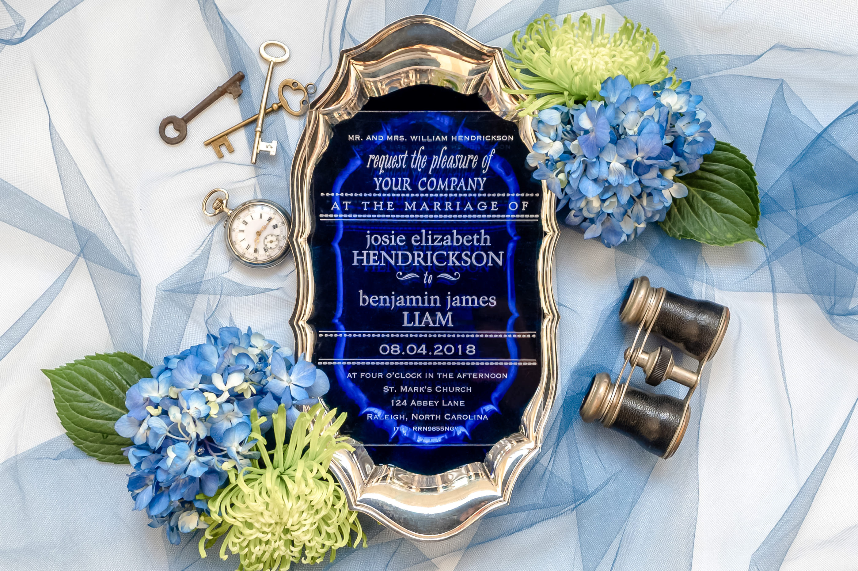 clear acrylic invitation with white writing photographed on dark blue background