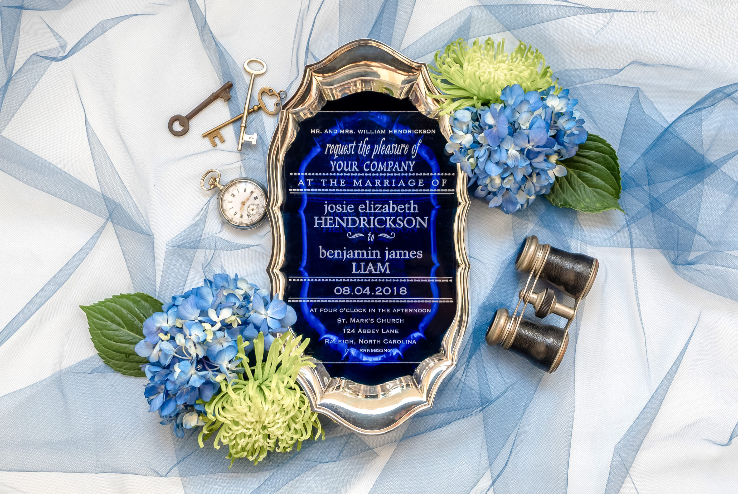 clear acrylic invitation with white writing photographed on dark blue background