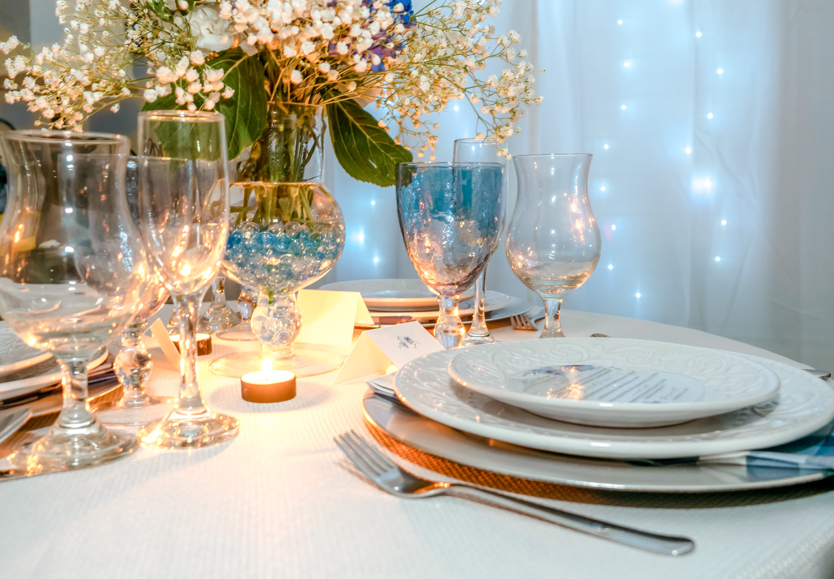 close photograph of reception table with place setting, candles, stemware, and floral centerpiece