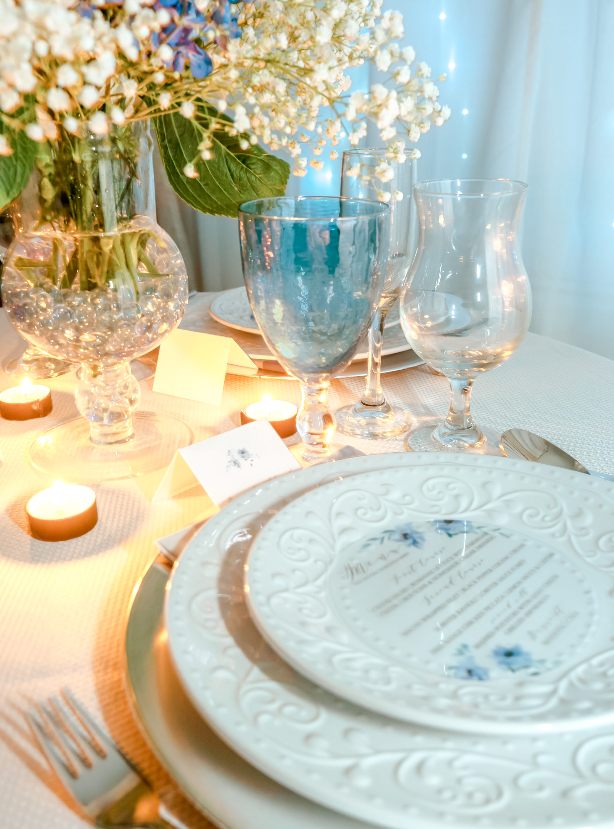 reception table with place setting, candles, stemware, and floral centerpiece