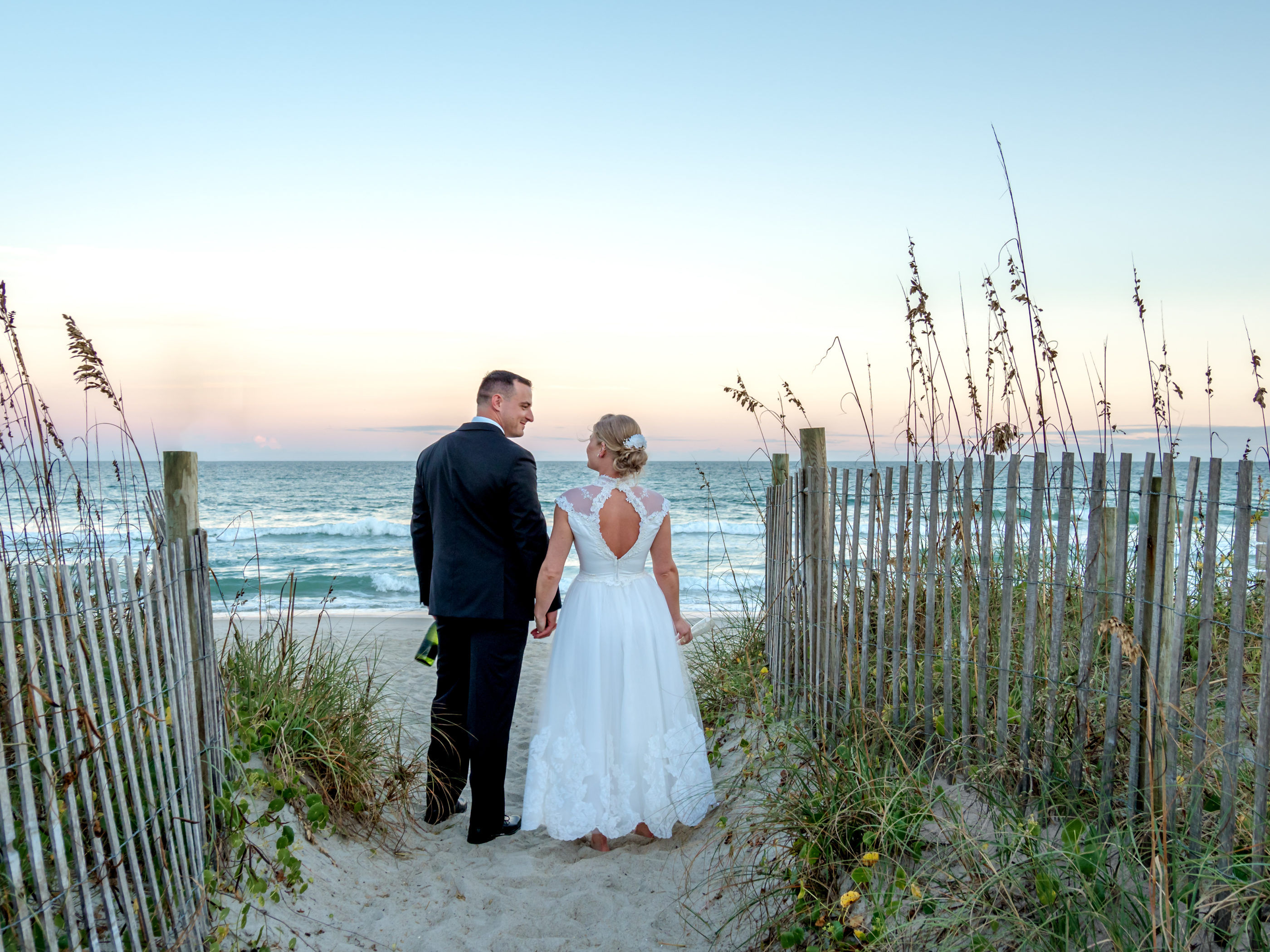 bride and groom looking at each other lovingly at the beach during sunset