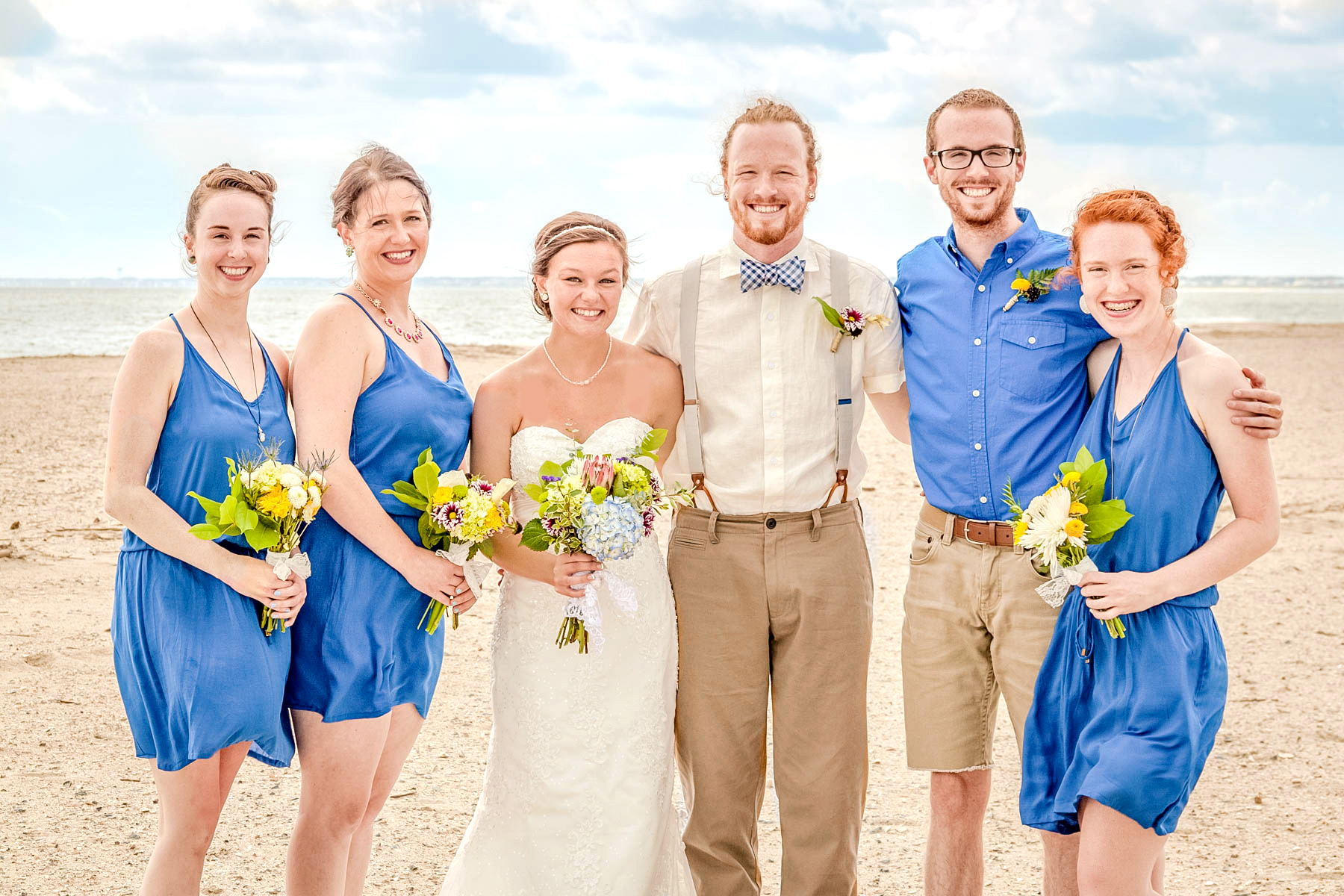 wedding part in royal blue with yellow flowers and the bride and groom at the beach