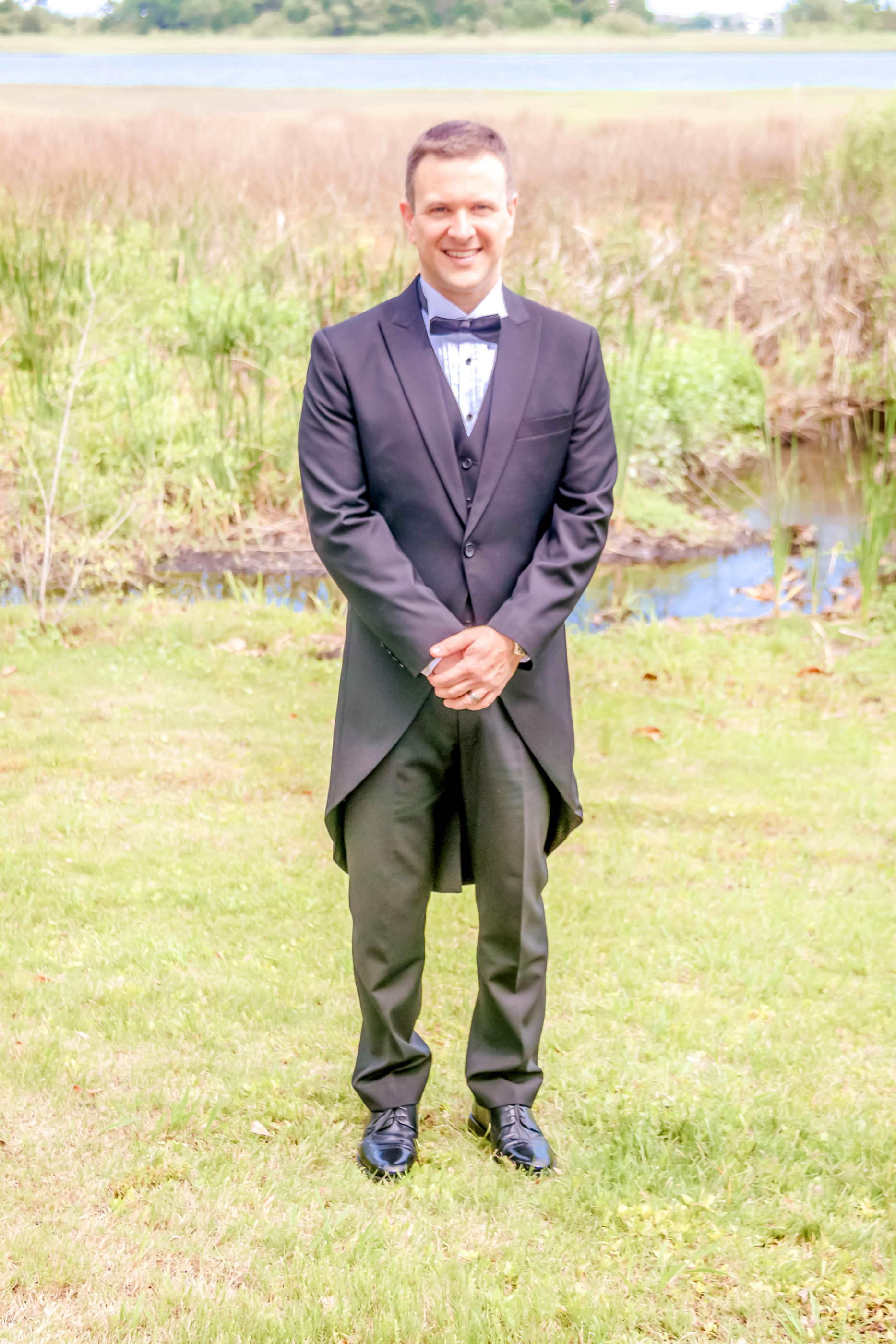 groom in tuxedo outside at lake