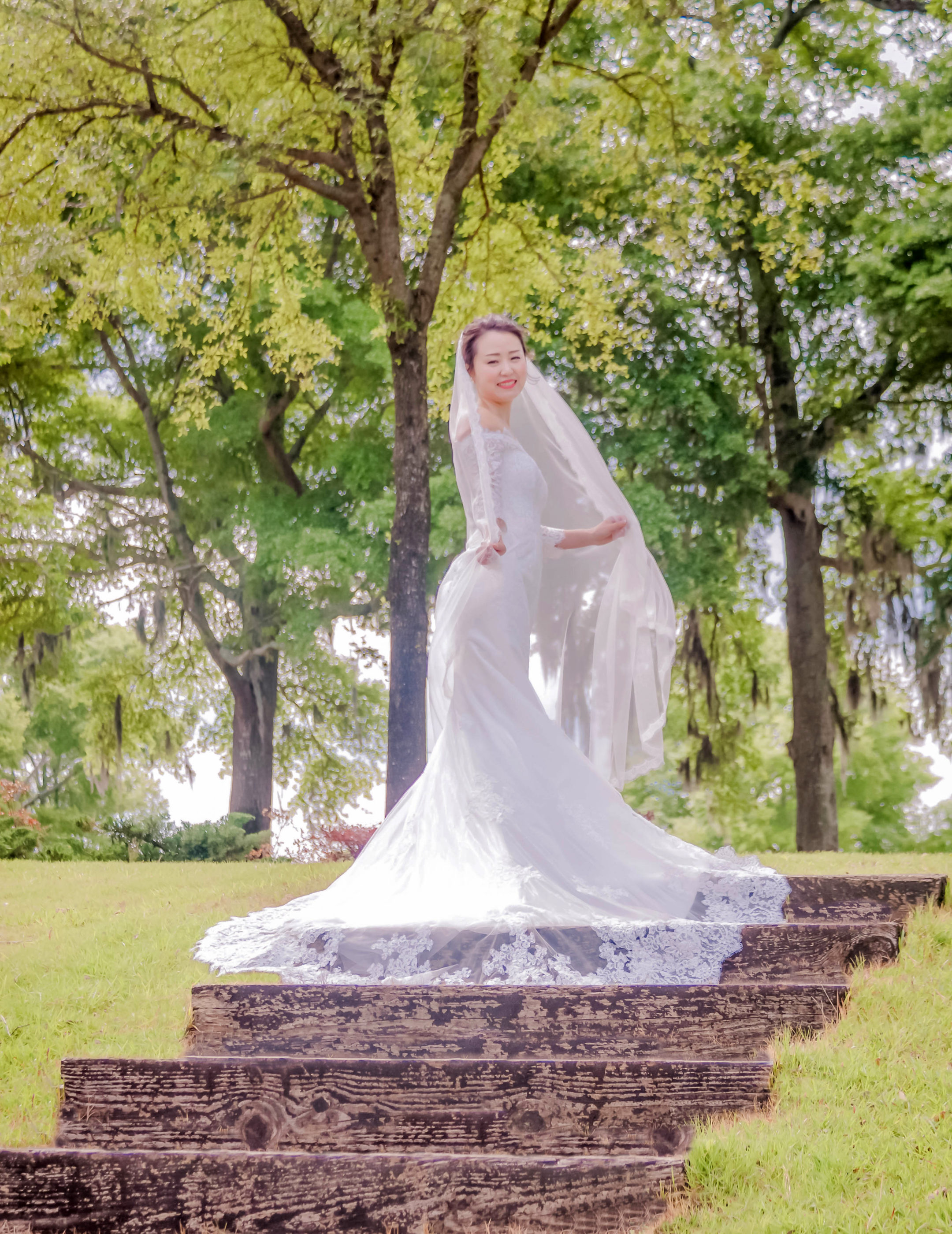 bride standing on stairs holding her veil outside