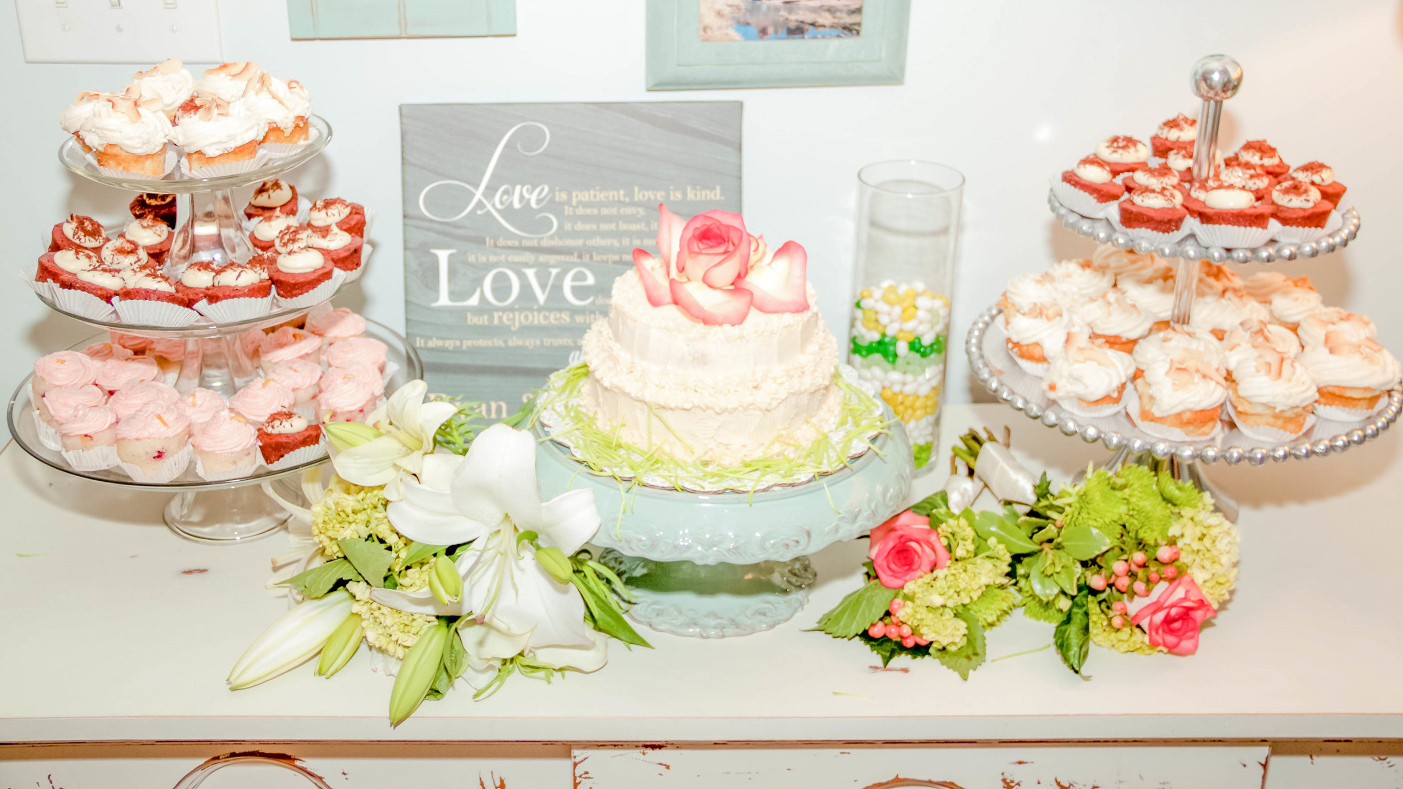 cake table with two tier wedding cake and multiple tiers of cupcakes and flowers