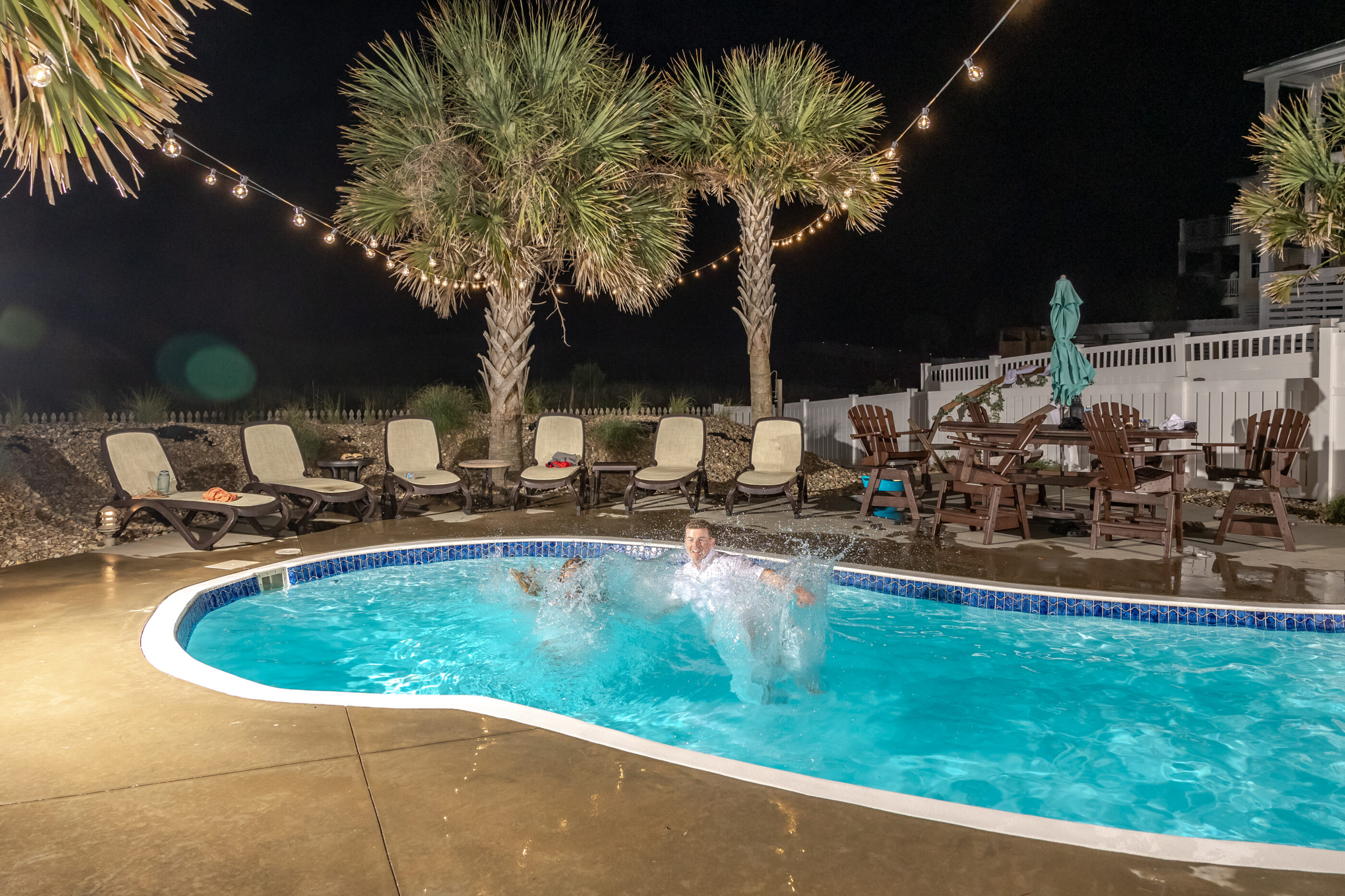 Bride and groom make a big splash in the pool during their nighttime wedding celebration.